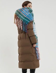 Detail of colorful rainbow plaid scarf with thick tassels paired with a brown winter coat