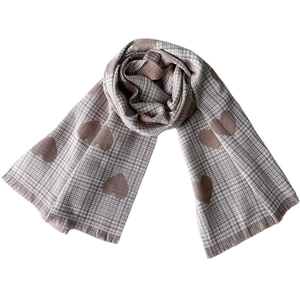 Detail of knit scarf with brown heart patterns, plaid texture, and soft tassel edges