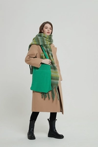 Elegante borsa a tracolla in maglia verde da donna abbinata a un cappotto beige