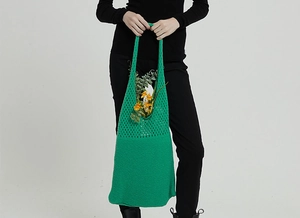 Dettaglio di borsa tote in crochet verde con motivo traforato e margherite