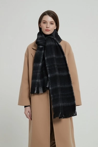Detail of a thick black and grey plaid scarf paired with a classic camel wool winter coat
