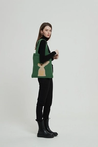 Scatto a figura intera di borsa tote in maglia verde con motivo a coniglio su modella