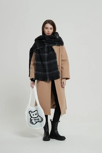 Detail of white knit tote bag with black bear pattern carried by a model in long coat