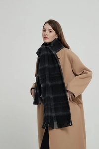 Close-up of black and grey checkered scarf with fringe on a camel cashmere coat