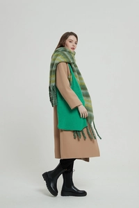 Dettaglio borsa in maglia verde con sciarpa in mohair a righe e cappotto di lana marrone