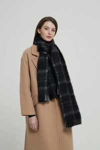 Close-up of black plaid scarf texture with soft fringe edges and premium woven fabric