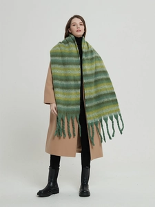 Detail of a thick winter striped scarf with gradient green tones and oversized fringe tassels