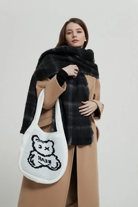 Detail of white knit tote bag featuring a black bear pattern and thick woven texture