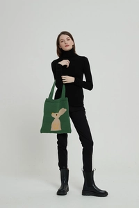 Dettaglio della borsa tote in maglia verde con motivo a coniglio marrone su tessuto
