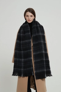 Detail of soft black plaid shawl scarf with fringed edges on a wool coat