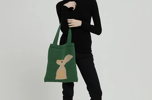 Dettaglio della borsa tote in maglia verde con motivo a coniglio beige e trama spessa