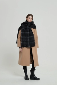 Close-up of black and grey plaid scarf texture with soft wool-like fabric and fringe