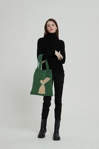 Borsa tote in maglia verde con motivo jacquard a coniglio beige portata da modella