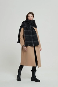 Detail of a thick black and grey plaid scarf paired with a stylish camel wool coat