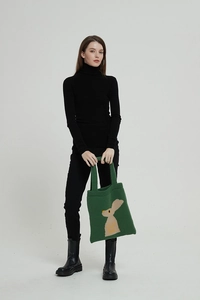 Dettaglio della borsa tote in maglia verde con motivo jacquard a coniglio marrone e trama