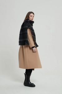 Detail of a black and grey plaid tassel scarf paired with a camel wool coat and boots