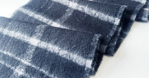 Close-up of thick grey plaid scarf fabric showing soft cashmere texture and fringe detail