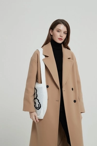 White knit shoulder bag with black cartoon sketch paired with camel wool coat