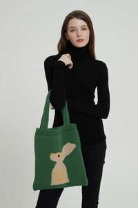 Dettaglio della trama a maglia e del ricamo a coniglio sulla borsa a tracolla verde