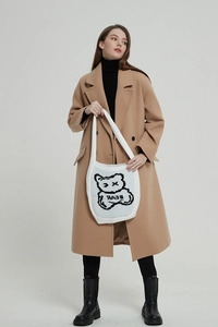 Close-up of white knit shoulder bag featuring a black and white bear pattern design