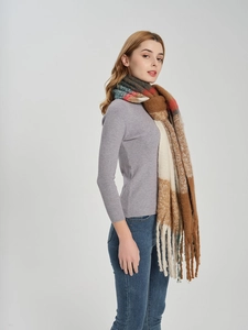 Detail of warm-toned plaid scarf with soft fringe trim and thick knit texture
