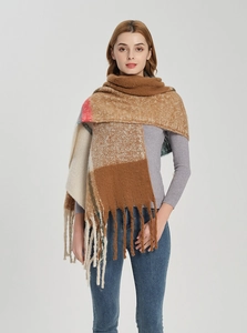 Detailed view of thick checkered scarf featuring long decorative fringe and earthy tones