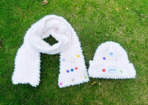 Detailaufnahme des weißen Plüsch-Wintersets aus Mütze und Schal mit bunten Zierknöpfen
