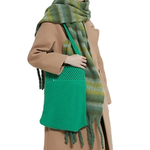 Borsa a spalla in maglia verde brillante con trama traforata indossata da modella in cappotto