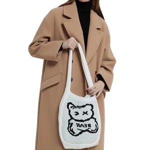 White knitted tote bag with black cartoon bear and BEAR text carried by a female model
