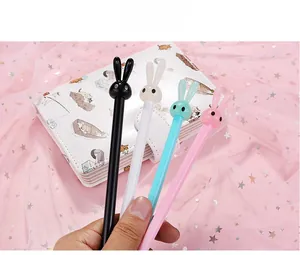 Detail view of colorful cartoon rabbit gel pens held against a cute notebook backdrop