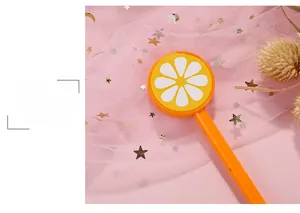 Detail eines süßen Orangen-Zitronen-Lollipop-Gelschreibers auf rosa Deko-Hintergrund