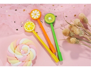 Nahaufnahme von Frucht-Gelschreibern mit Zitrone, Orange und Kiwi auf rosa Tüll