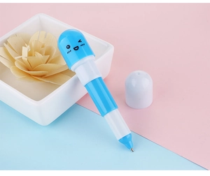 Vue détaillée d'un mini stylo bille en forme de capsule avec visage de dessin animé