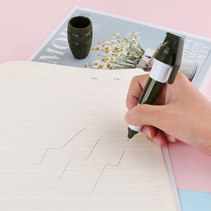 Creative grenade-shaped mini ballpoint pen being used for writing on a notebook