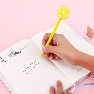 Süßer Gelstift mit gelbem Zitronen-Lollipop und Frucht-Dekor auf liniertem Notizbuch