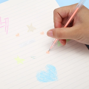 Transparent orange ink gel pen for journaling and drawing on a notebook held by hand