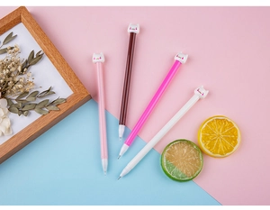 Detail of four colorful cat-themed gel pens on a pastel background with decorative props