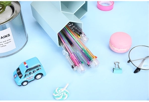 Macro detail of multi-color ballpoint pens inside a blue hexagonal desktop pencil holder