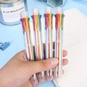 Transparent 8-color retractable ballpoint pen set held by hand against a blue desk setup