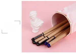 Eco-friendly kraft paper pens in a marble holder against a pink background