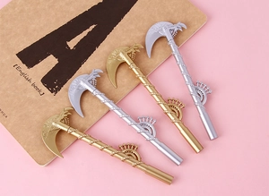 Detail of four creative scythe-shaped gel pens in gold and silver finish on a notebook
