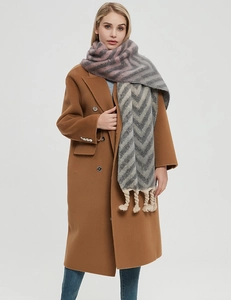 Detail of chunky knit scarf with tassels paired with a brown double-breasted coat