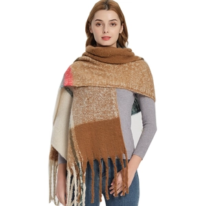 Thick plaid winter scarf with fringe in brown and beige tones worn by a model