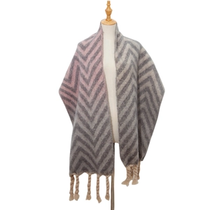 Detail of herringbone wave knit shawl with pink and grey tones and chunky braided tassels