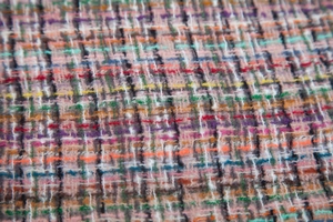 Macro view of multi-color tweed fabric with textured pink, black and yellow woven threads