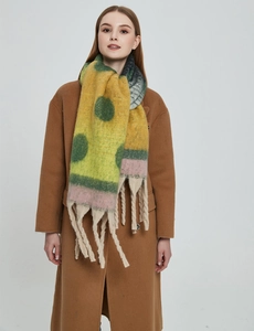 Close-up of thick knit shawl with colorful polka dots and long tassel trim details
