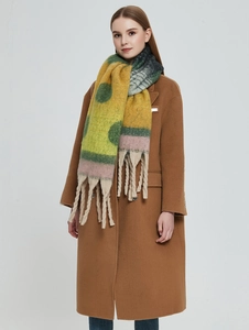 Detail of colorful geometric shawl with polka dots, thick knit texture, and white tassels