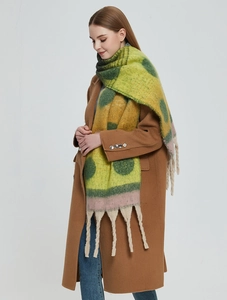 Detail of thick knit scarf showing bold yellow dots and long beige chunky fringe accents