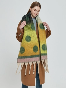 Detail of winter thick shawl featuring green polka dots and chunky twisted tassels