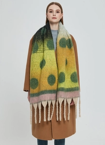 Close-up of thick gradient polka dot scarf with chunky tassels on wool coat